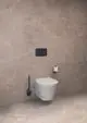 Wandhängendes WC in Weiß vor einer neutralen, hellen Wand, ergänzt durch eine Bürstengarnitur in Schwarz und eine Papierrolle. Ideal Standard Zubehörteile sichtbar.